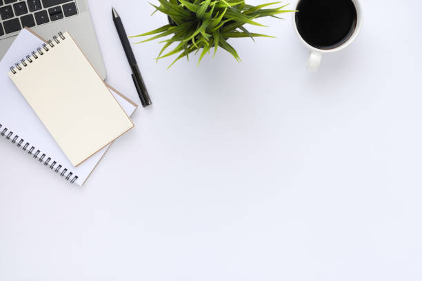 istock Top view above of White office desk table with keyboard, notebook and coffee cup with equipment other office supplies. Business and finance concept. Workplace, Flat lay with blank copy space. 1292727458