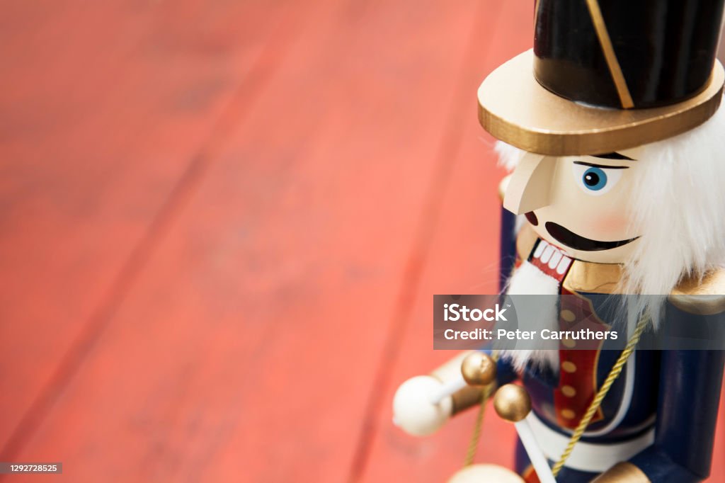 Close-up of a wooden soldier nutcracker figurine on a red wooden surface with copy space Traditional Christmas decoration originating from Germany Nutcracker Stock Photo