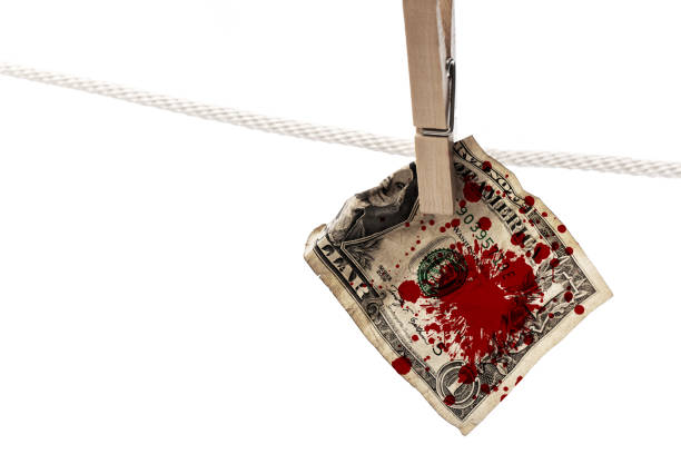 Concept of illegal and criminal earnings - Splattered with a blood US dollar banknote Splattered with a blood US dollar banknote is hung on a rope with clothespin. Concept of illegal and criminal earnings. bloody money stock pictures, royalty-free photos & images