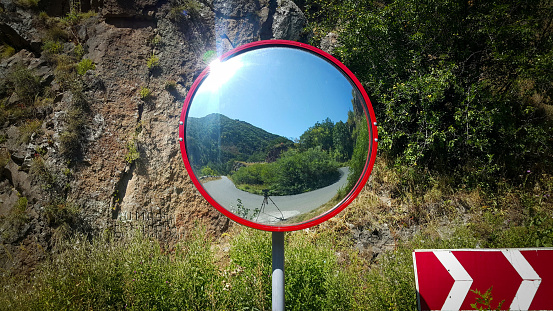 Road mirror. Round mirror placed on the turn on the road for safe driving. Road sign of turn. Transport theme about roads.