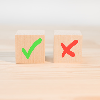 Concept of positive or negative decision making or choice of approval or rejection. Tick mark and cross mark x on wooden cubes. Wooden blocks with green check mark and red x.