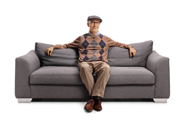 istock Elderly man seated on a sofa resting and smiling 1292730635