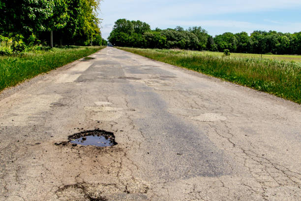 istock Bumpy Pothole Ridden Road With Patches In Rural Michigan 1292730668