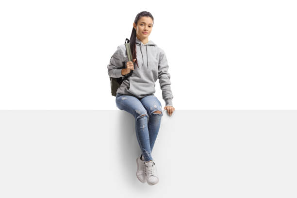 istock Mixed race female student sitting on a blank board and smiling at camera 1292731792