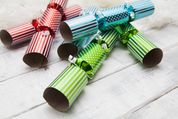 istock Stack of shiny paper Christmas crackers on a white rough wooden surface 1292732265