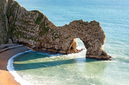Natural coastal limestone cliffs eroded on the Jurassic Coast form geological coastal features such as the natural arch of the famous Durdle Door
