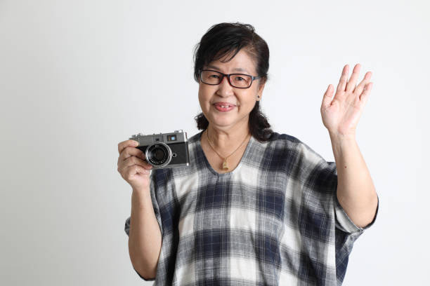 The elder Asian woman standing on the white background.
