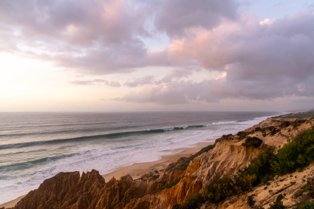 Many bizarre eroded sand dunes on the Atlantic Ocean with waves rolling in at sunset