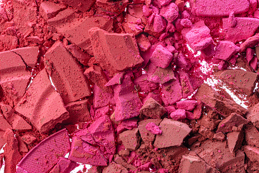 Background of smashed pink blush cosmetic powder. close up.