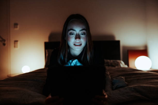 Young woman relaxing on bed watching movie on Digital Tablet Computer