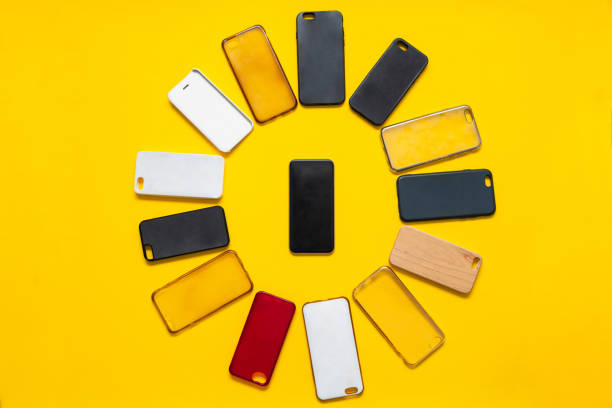istock Pile of multicolored plastic back covers for mobile phone on yellow background. Choice of smart phone protector accessories. A lot of silicone phone backs or skins next to smart phone 1292740121