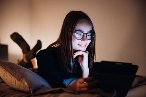 istock Teenage Girl relaxing on Bed at Night using her Digital Tablet Computer 1292740544