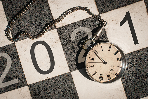 Waiting for 2021 concept. A new year's sign with a vintage pocket watch over black and white marble chessboard.