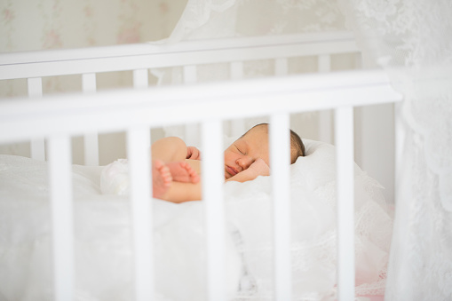 Cute newborn baby sleeping in crib. Bedtime