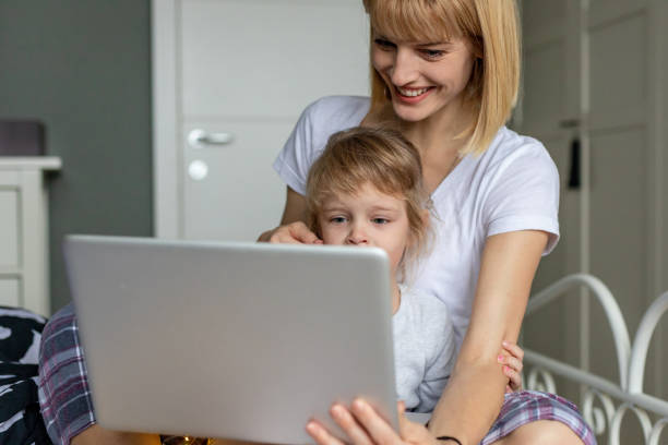 istock Mother and daughter in bed, looking at laptop 1292748403
