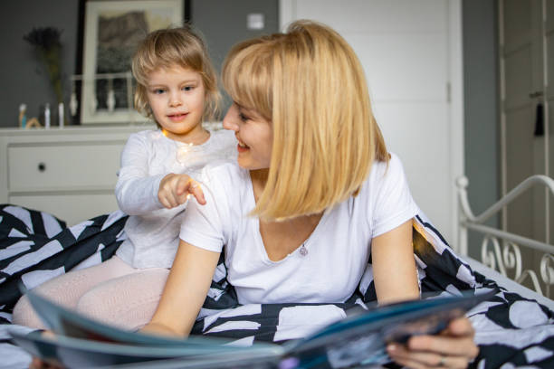 istock Mother and daughter playing and reading a book 1292748638