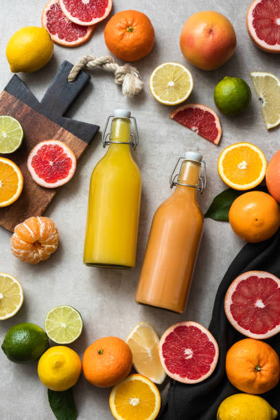 Freshly squeezed citrus juice in bottles with fresh fruits on concrete kitchen table