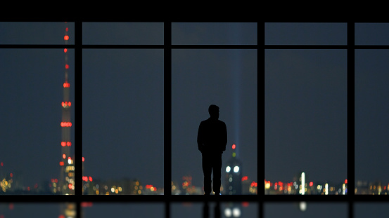 The man standing near the panoramic window on the city background