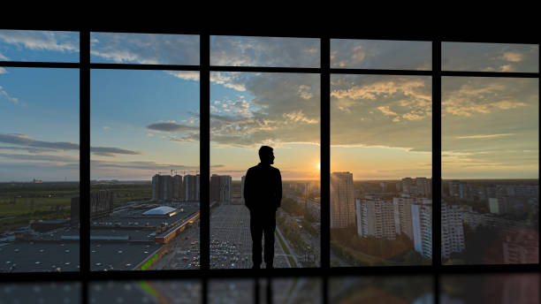 istock The man standing near the panoramic window on the sunset background 1292751002