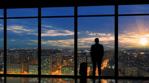 istock The male with suitcase standing near the panoramic window with a sunset 1292751136