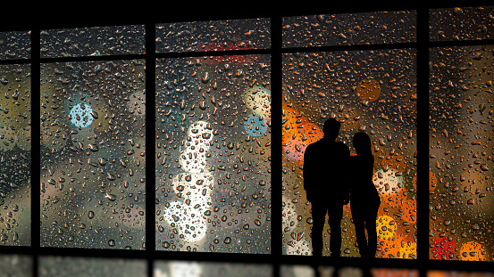 The couple standing near the wet panoramic window