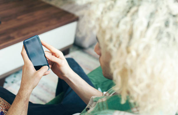 istock Young man on a couch at home, using mobile phone 1292751352