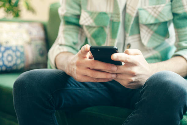 istock Young man on a couch at home, using mobile phone 1292752073