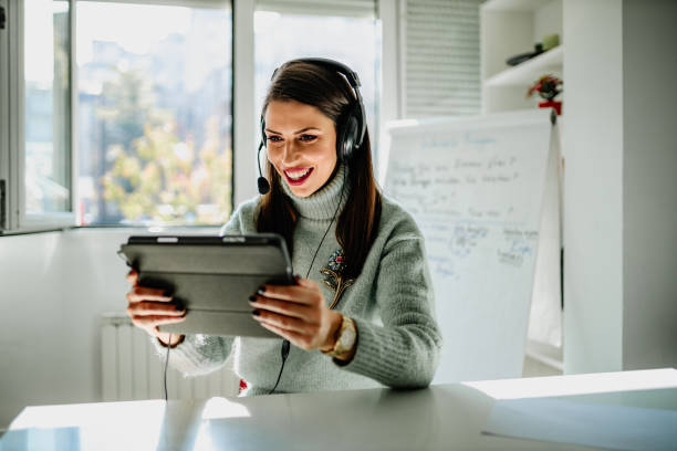 istock Woman teacher using headphones and digital tablet teaching from home 1292753367
