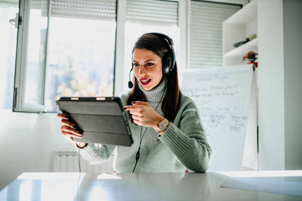 istock Teacher using headphones and digital tablet and teaching online 1292753370