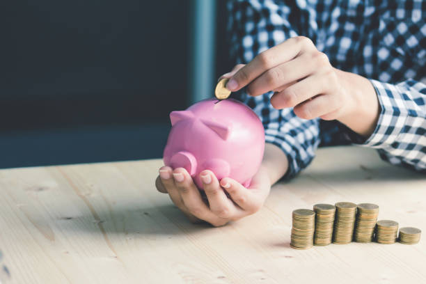 istock Saving,  hand putting a coin into piggy bank. 1292753811