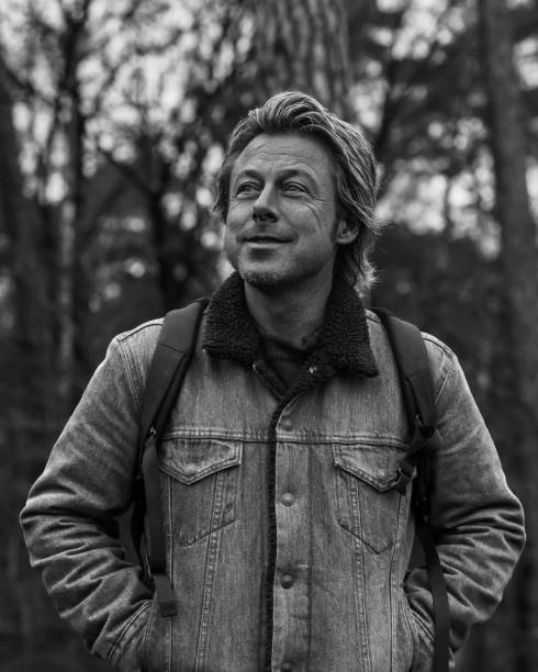 istock Happy man in jeans jacket with backpack in forest. Black and white photo. 1292753879