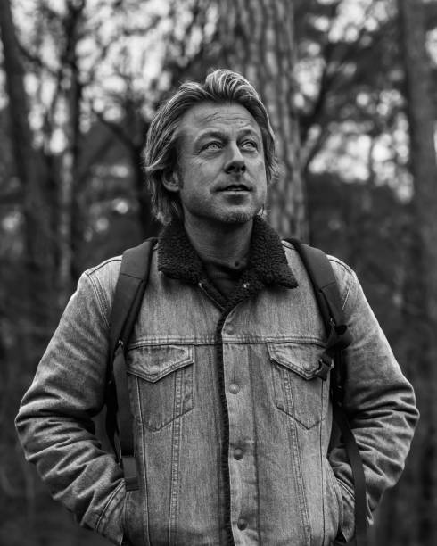 istock Man in jeans jacket with backpack in forest. Black and white photo. 1292753883