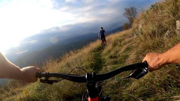 istock Mountain bikers ride through grassy meadow in the morning 1292753981