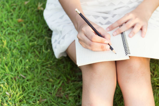 istock girl with pen writing on notebook on grass outside 1292754226