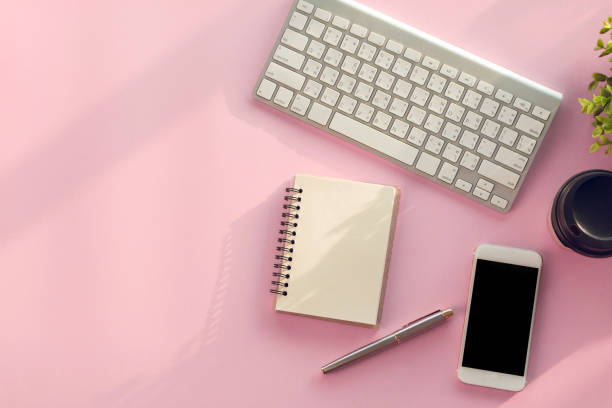 istock Modern pink office desk table  with  notebook for input the text in the middle. Top view, flat lay. 1292754373