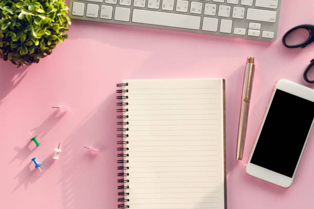 istock Modern pink office desk table  with  notebook for input the text in the middle. Top view, flat lay. 1292754383
