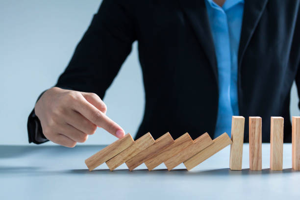 istock businessman hand taking Falling wooden Dominoes effect from continuous toppled or risk, strategy and successful intervention concept for busine 1292755054