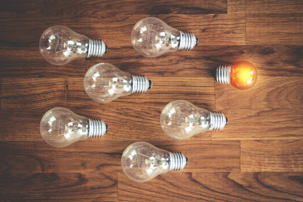 istock glowing bulb uniqueness concept. many bulbs on brown wooden table 1292755228