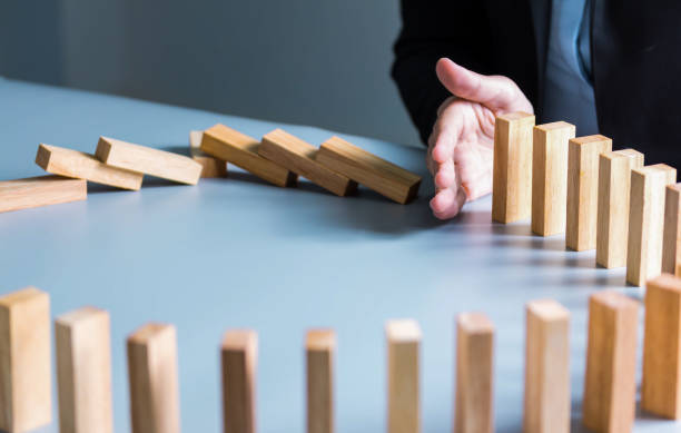 istock Businessman hand stop dominoes continuous toppled or risk with copyspace. Business risk, strategy and planing concept idea. 1292755292