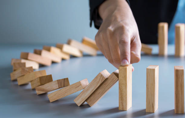 istock businessman hand stop dominoes continuous toppled or risk with copyspace 1292755300