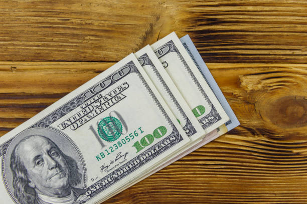 istock Stack of one hundred dollars bills on wooden desk 1292756857