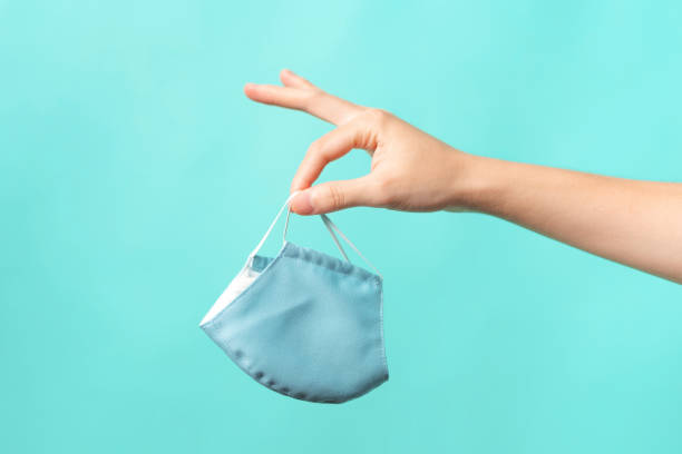 istock hand with a mask Face removal Masking on blue isolated background, concenpt coronavirus 1292759256