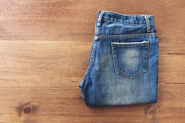 istock Blue jeans folded on white wooden background 1292760043