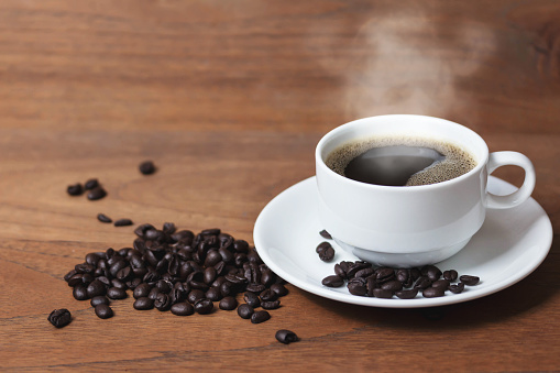 Taza de café caliente con granos de café en la mesa de madera photo