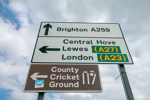 A road sign to Sussex County Cricket Club in Hove, England, with a sticker visible at bottom left