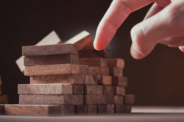 istock hand stopping risk the wooden blocks town from falling - Image 1292760305