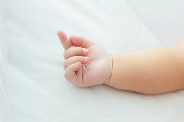 istock hand  baby lying on a bed while sleeping in a bright room 1292760406