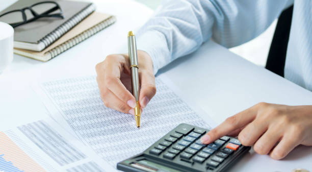 istock Close up young woman with calculator counting making notes at home, hand is writing in a notebook. Savings finances concept. 1292761061