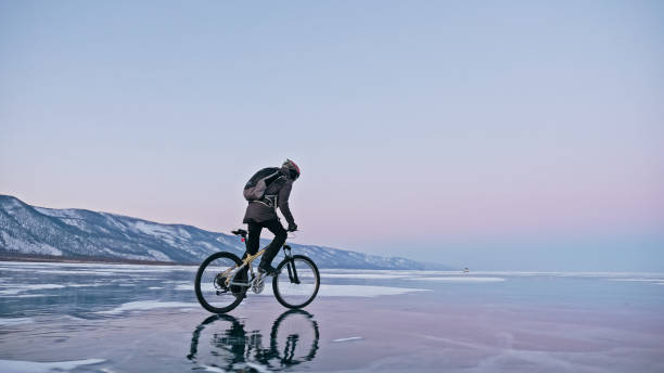 Man is riding bicycle on the ice. Ice of frozen Lake Baikal. Tee stock photo