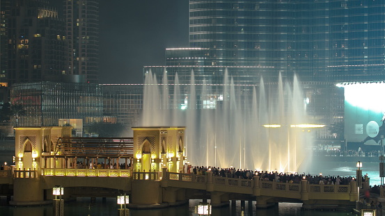 The bridge with walking people near the biggest musical fountain in Dubai, UAE timelapse 4K
